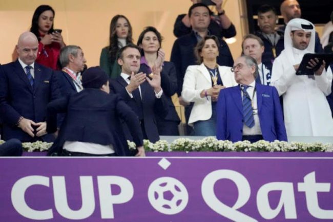 Emmanuel Macron berdiri memberi dukungan timnas Prancis saat melawan Maroko di semifinal Piala Dunia 2022. (Foto: yahoosports)
